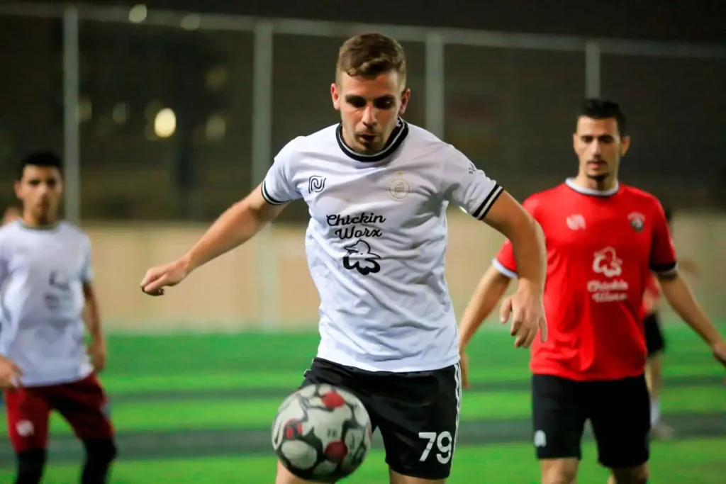 Man speelt voetbal in een wit Beyond Wear T-shirt